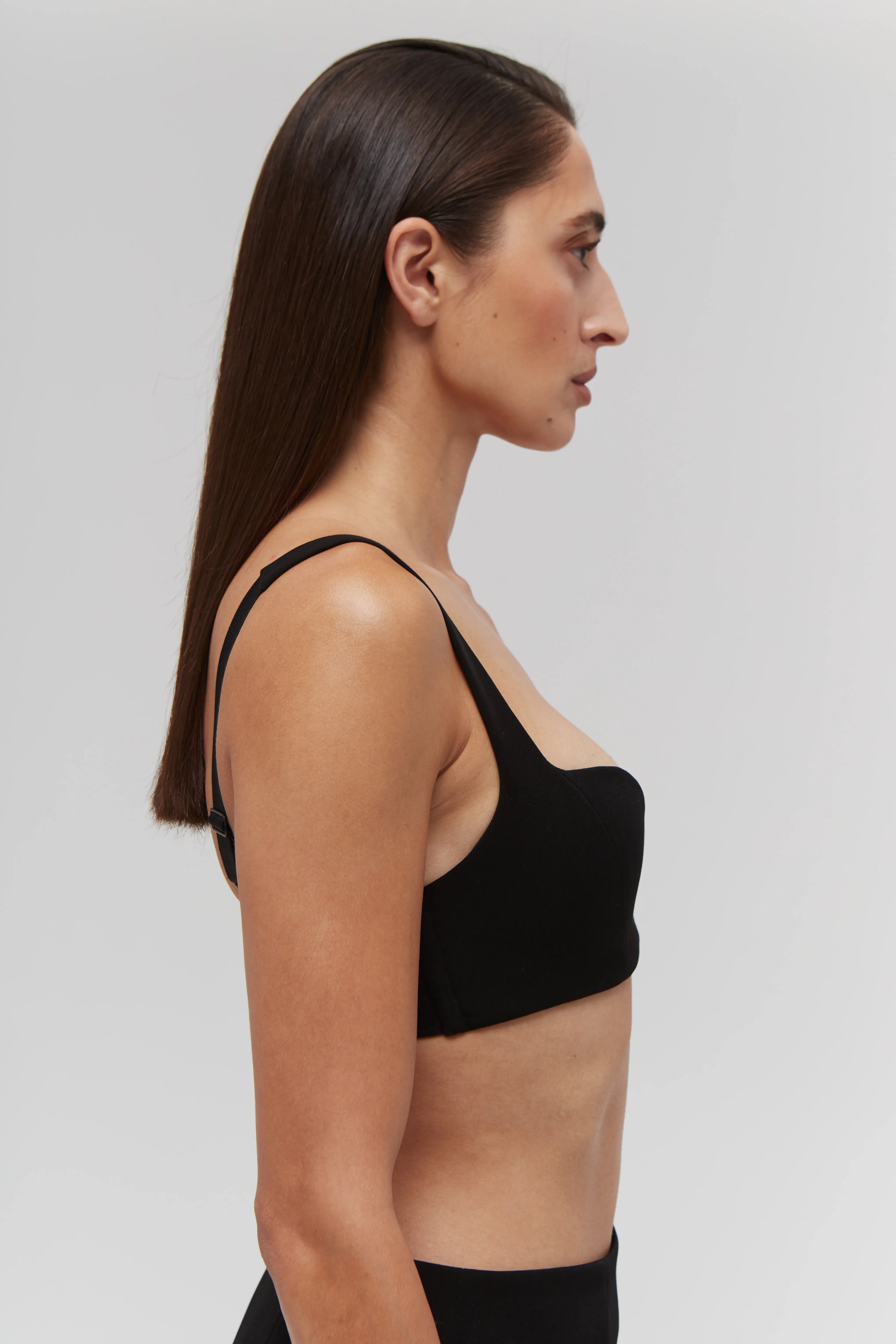 Woman wearing a black non-lingerie bra top against a plain background