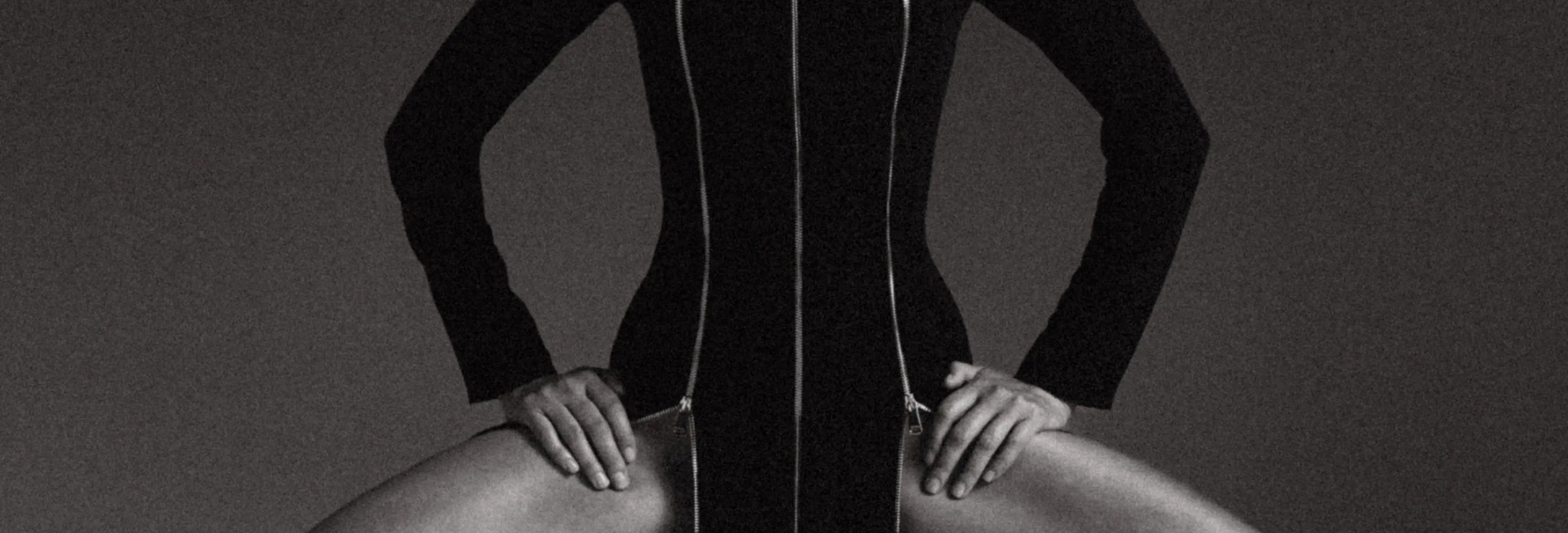 Black and white image of a person wearing a form-fitting dress against a dark background