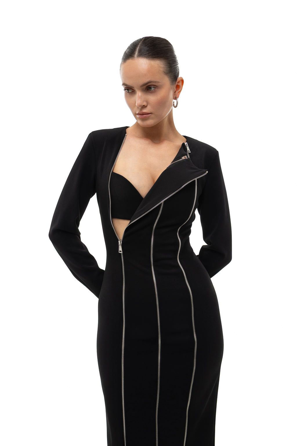Woman wearing a black midi evening dress with three silver zippers on a white background. 