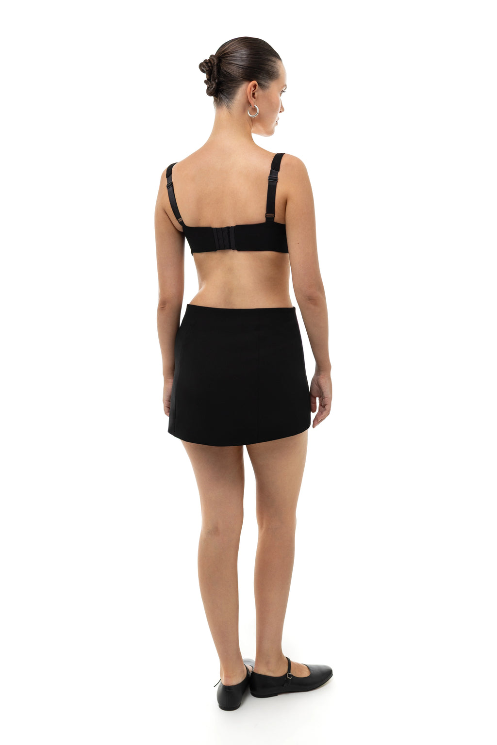 Woman wearing a black bra top, non-lingerie, and mini skirt set on a white background