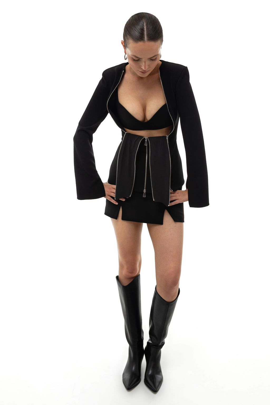 Woman wearing a black outfit with a jacket, top, and skirt on a white background. Soluje