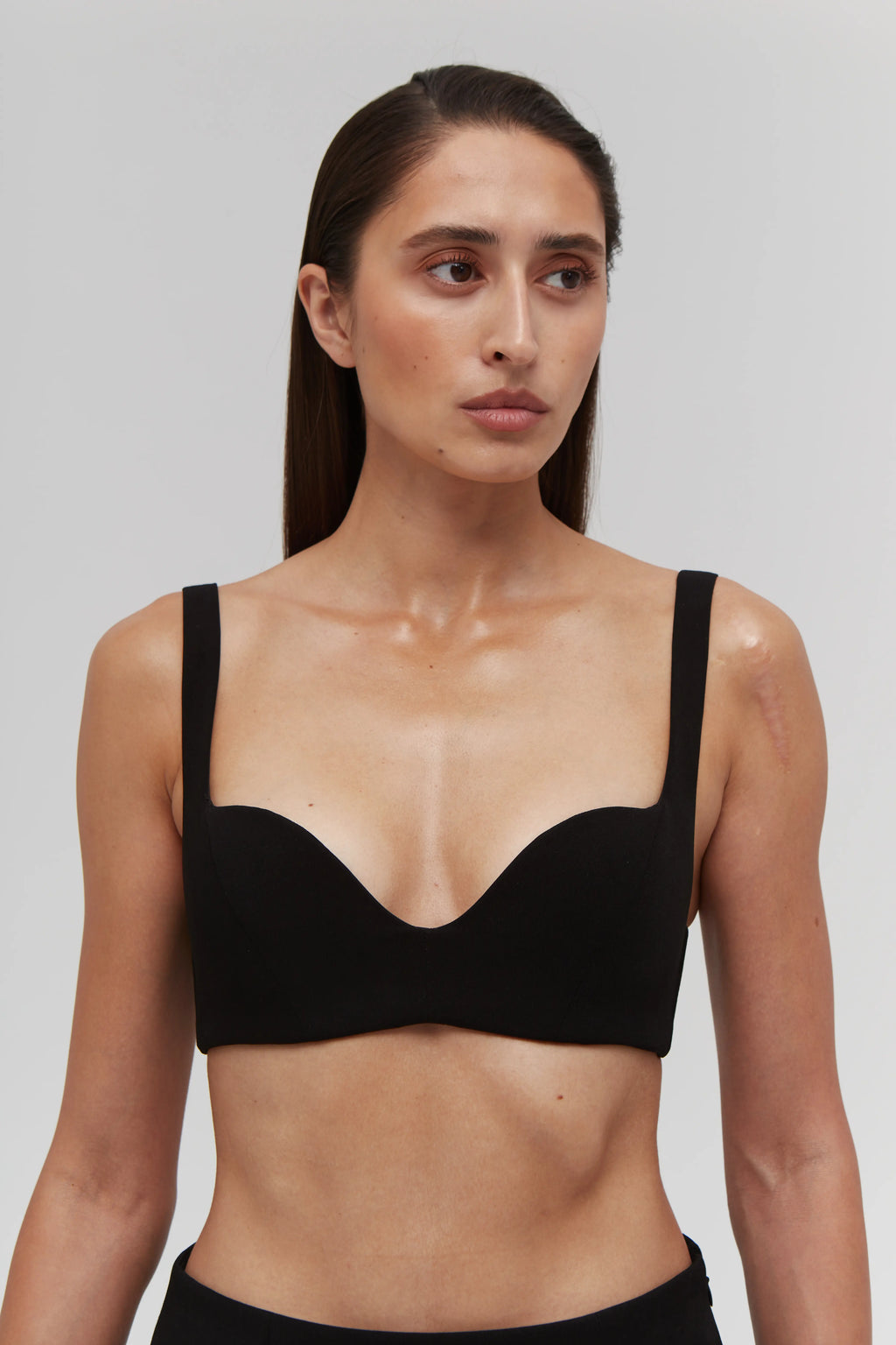 Woman wearing a black bralette top against a plain background
