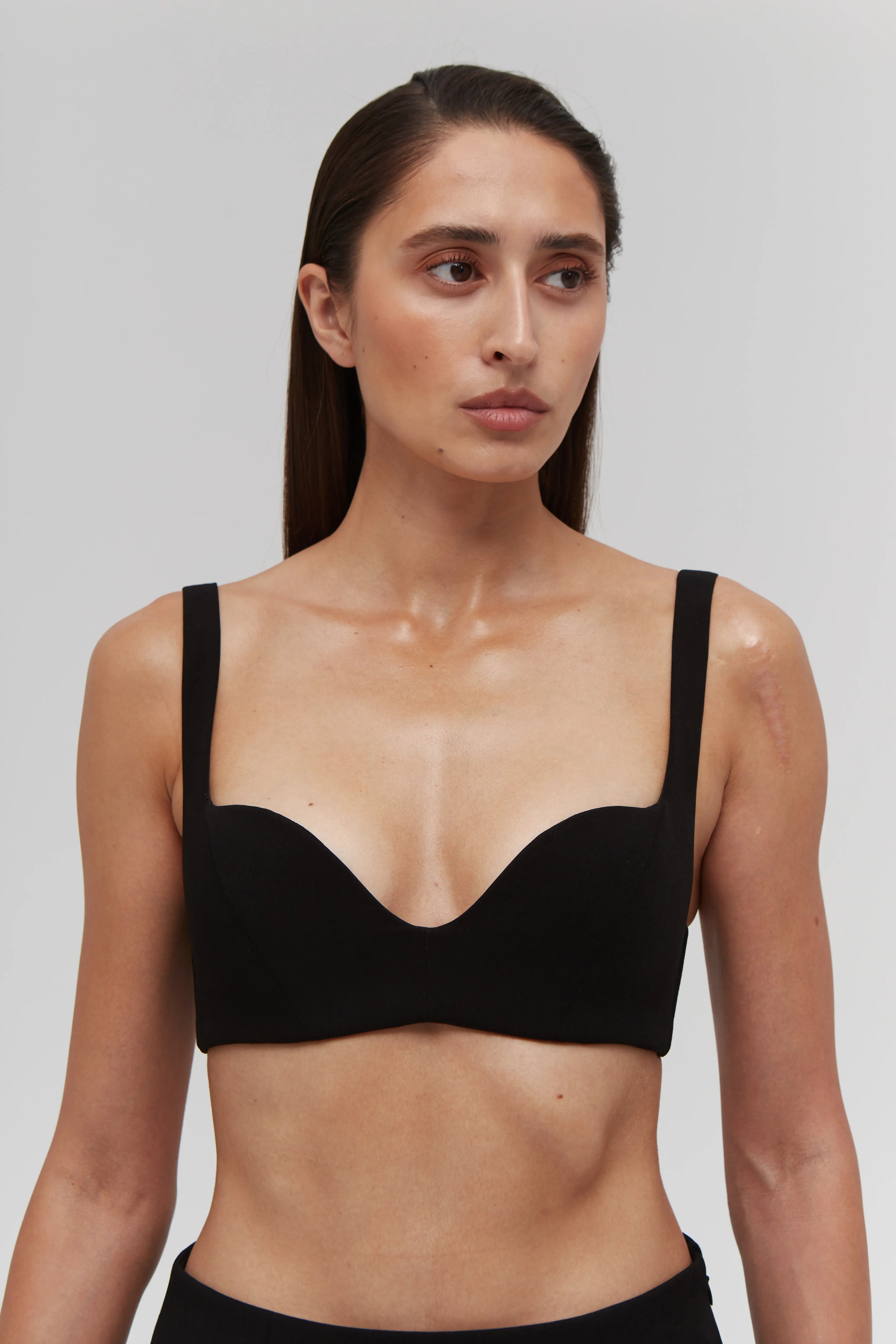 Woman wearing a black bralette top against a plain background