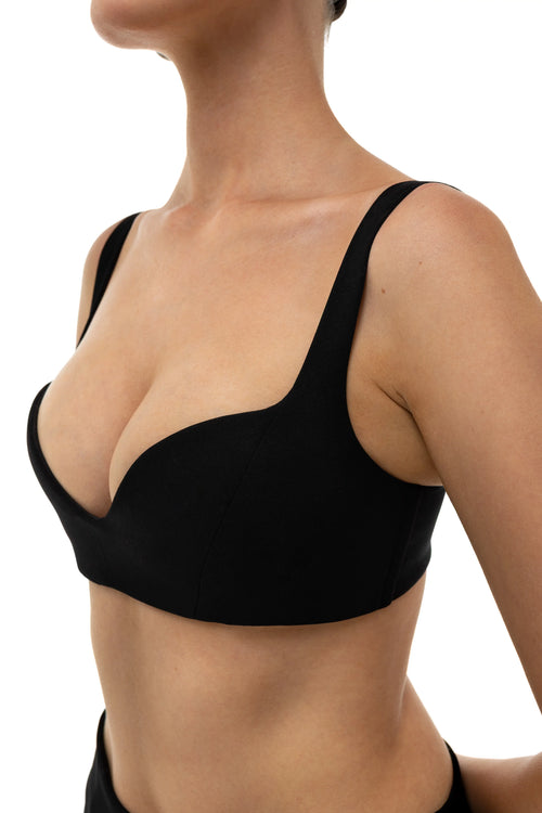 Black non-lingerie bra top worn by a person on a white background. Sleek look