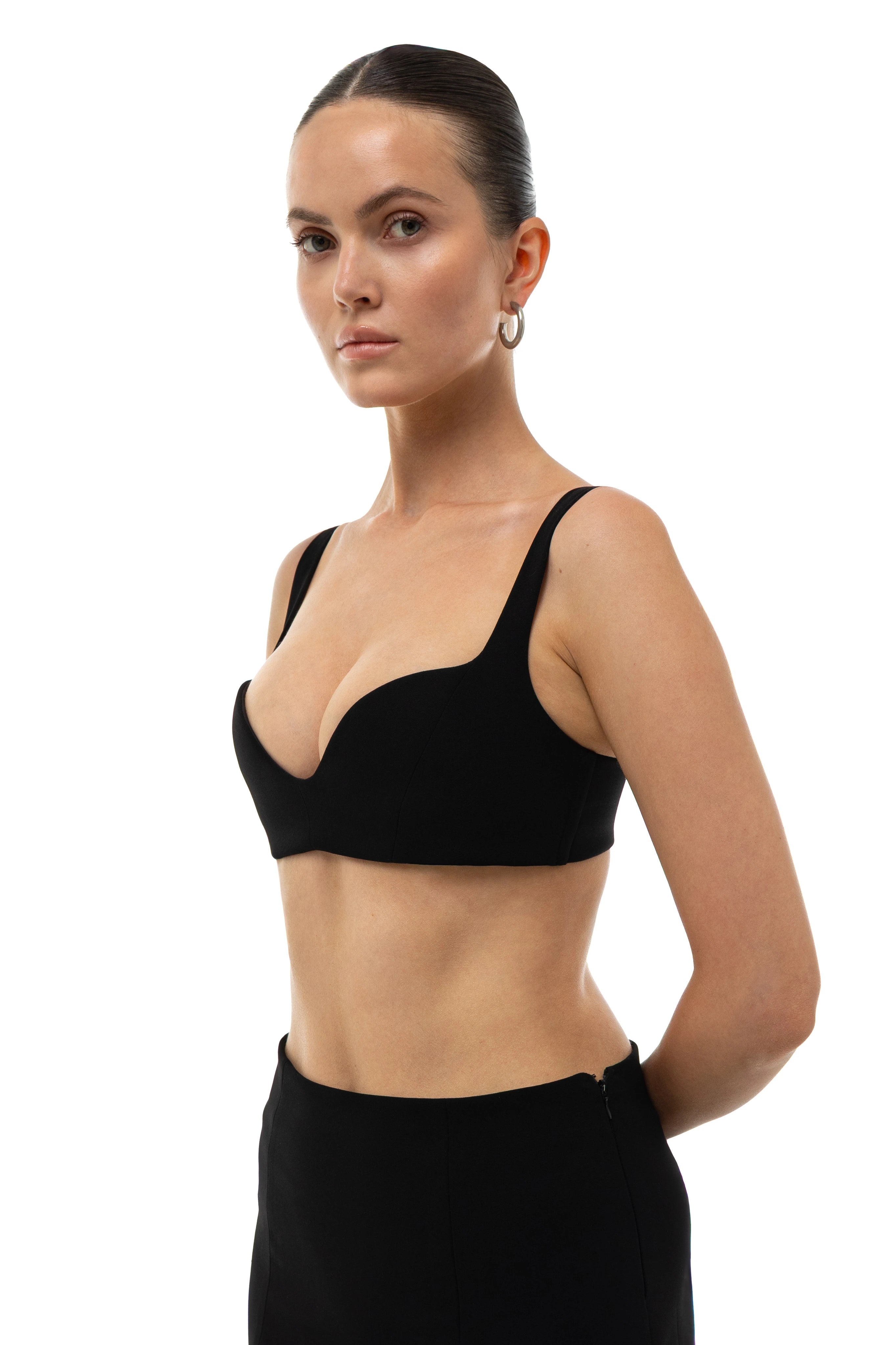Woman wearing a non-lingerie black bra top and black mini skirt  on a white background. 