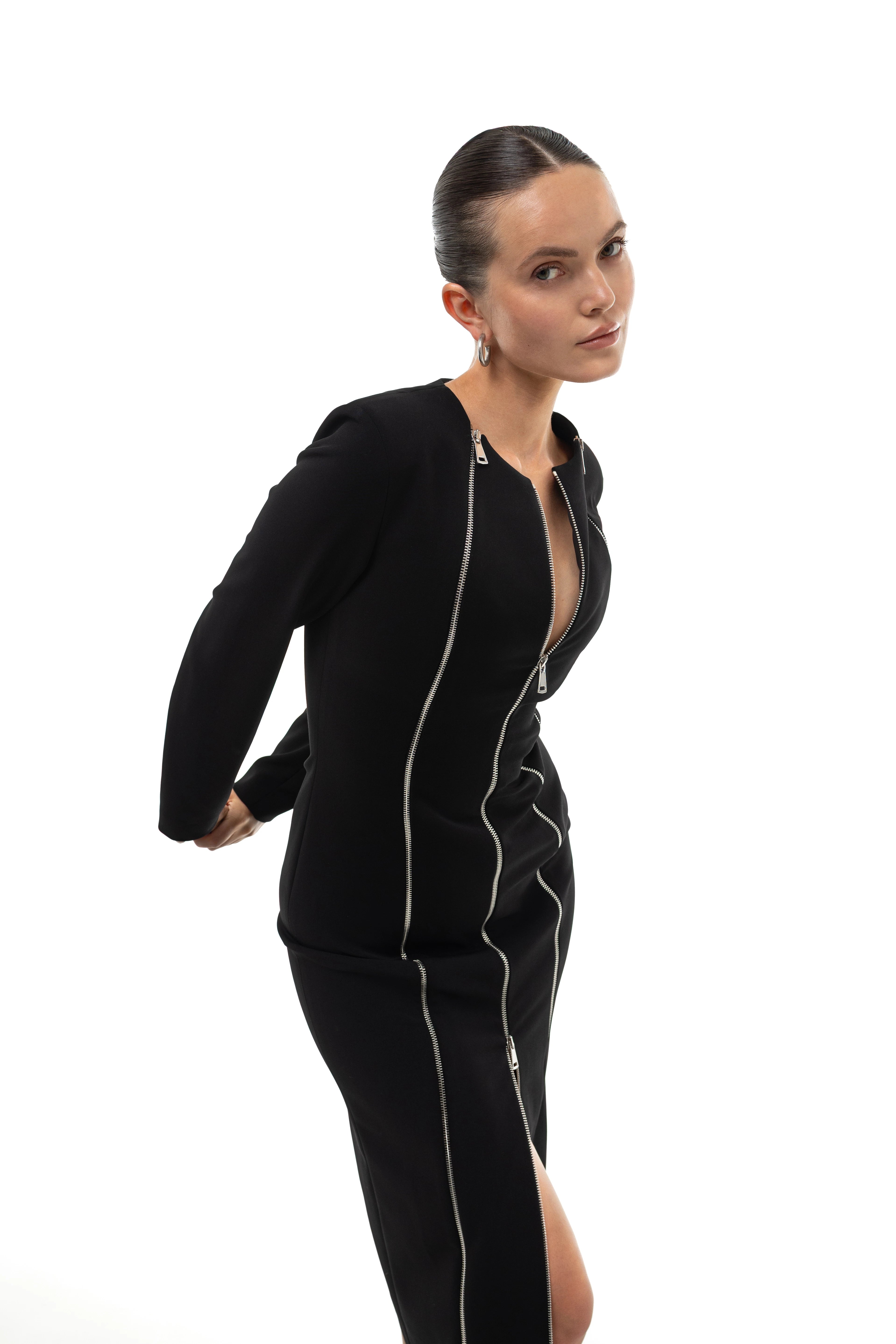 Woman wearing a black midi dress with three silver zippers on a white background. Soluje