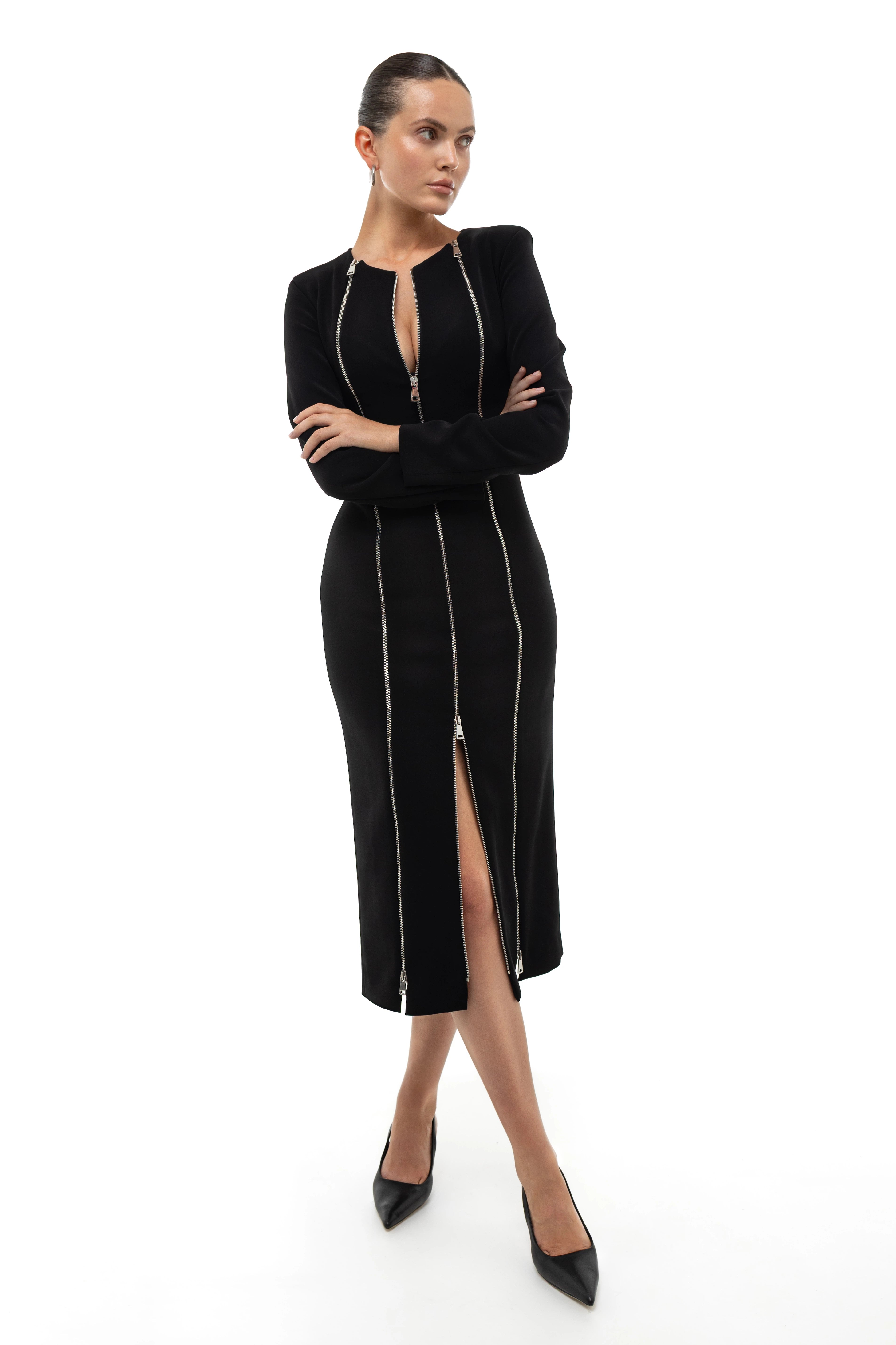 Woman wearing a black midi dress with silver zippers on a white background.