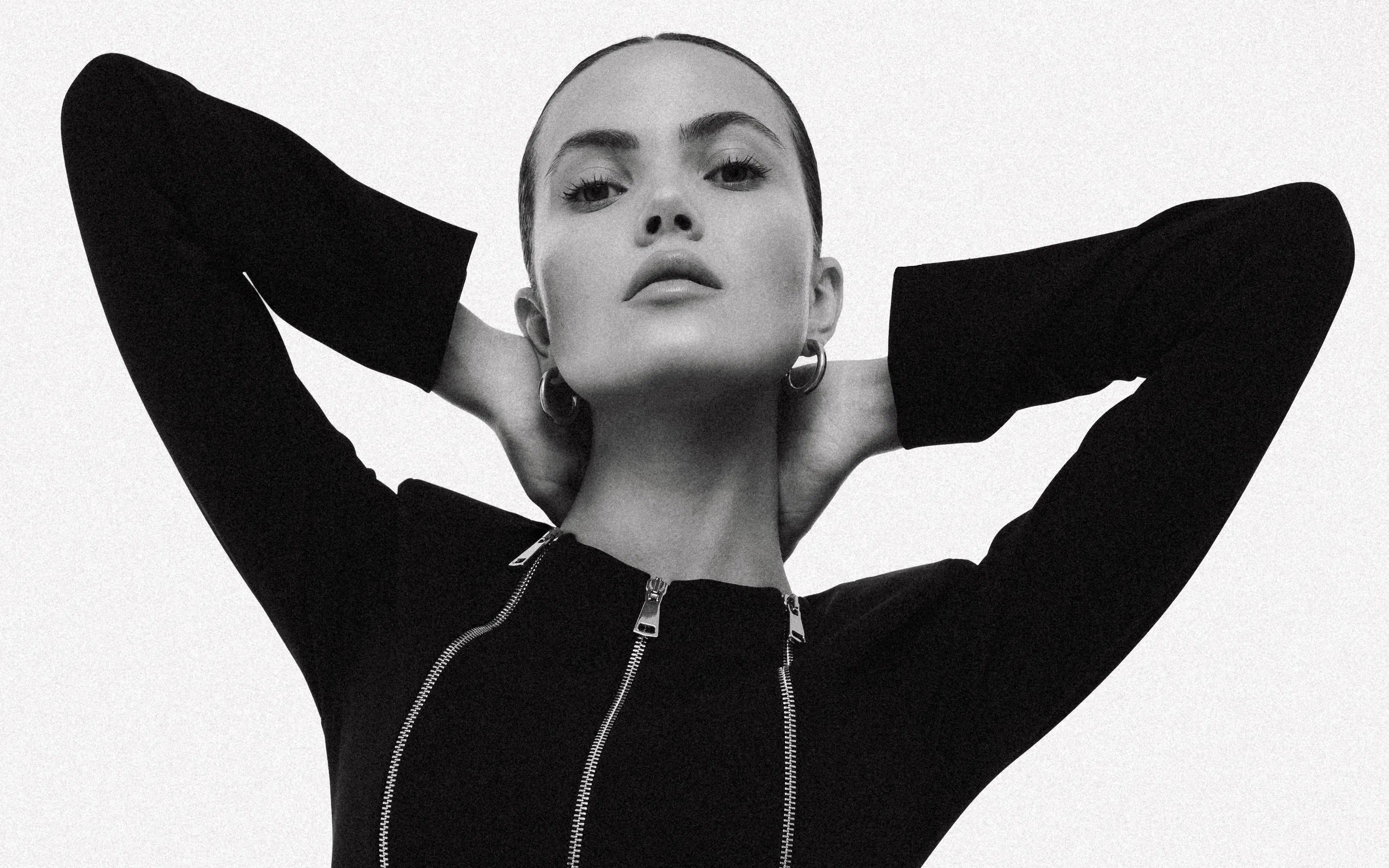 Black and white portrait of a person wearing a black outfit with three silver zippers. soluje 